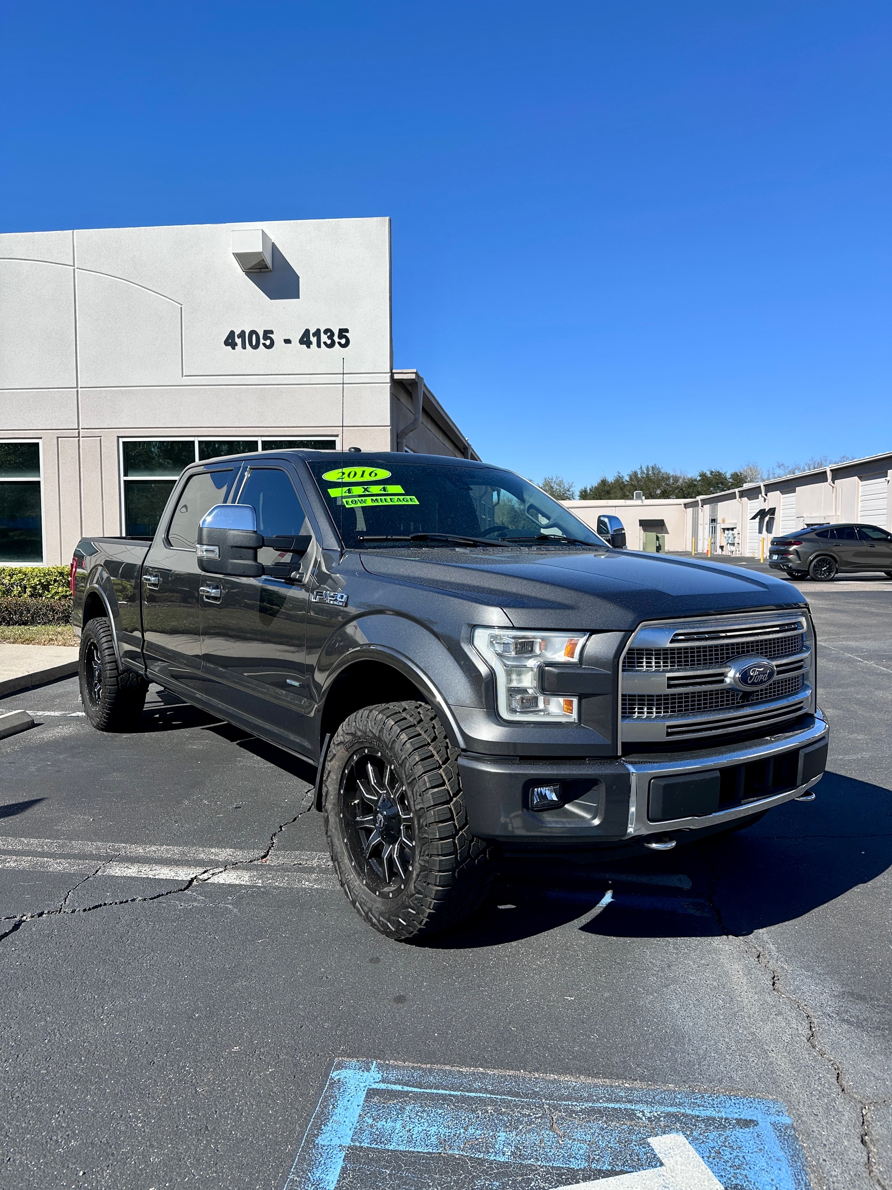 Dark gray 2016 Ford F-150 4x4 pickup truck with off-road tires parked outside.