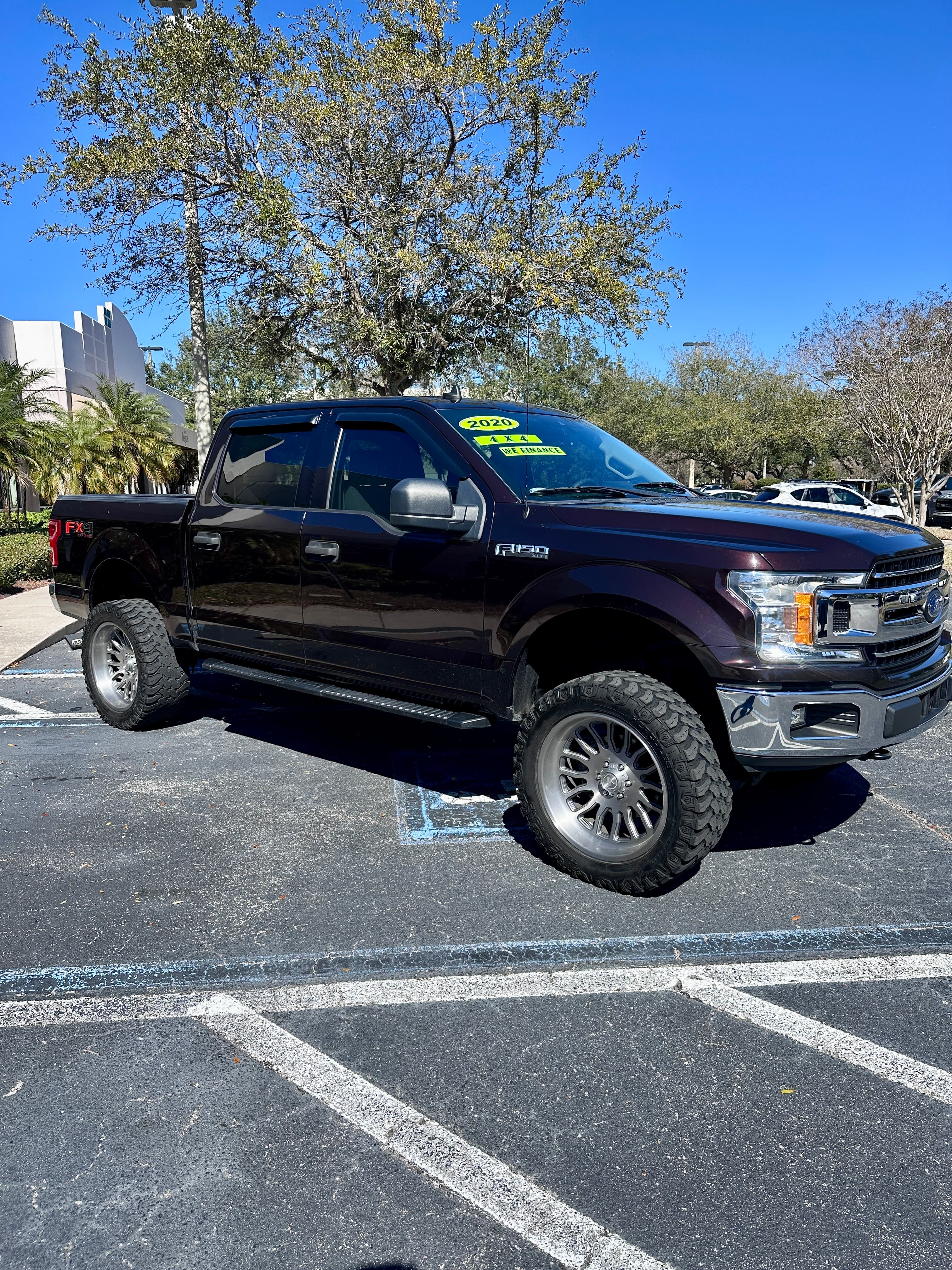 Dark maroon lifted 2020 Ford F-150 truck with large off-road tires and silver rims.