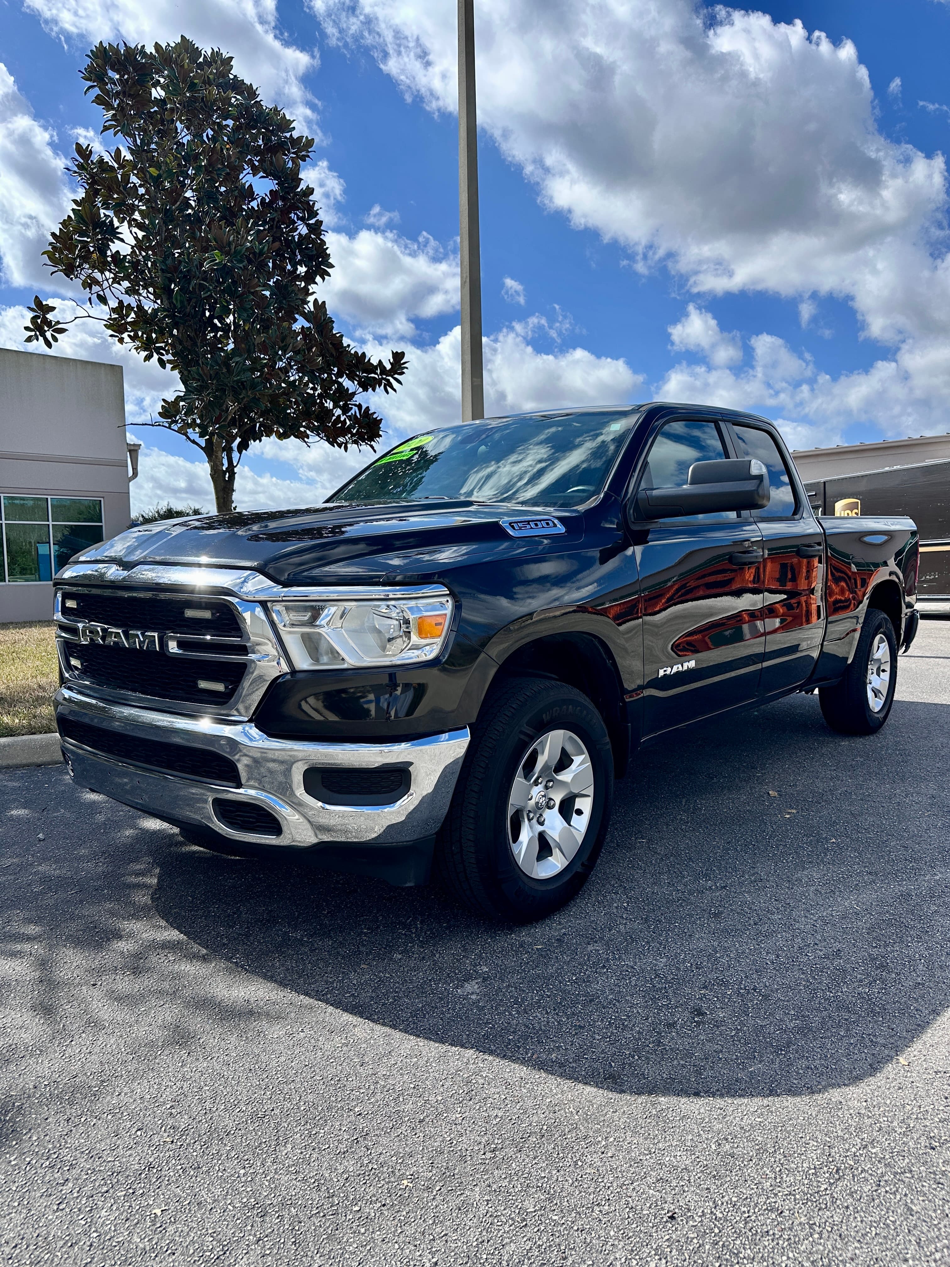Black RAM 1500 pickup truck with chrome accents parked on asphalt under a cloudy sky.
